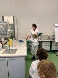 2021 - Gläsernes Labor - 01 - Lehrerin und Mädchen vor Gefäß